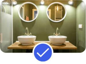 Modern bathroom interior with green walls, double round mirrors, and elegant white sinks on a wooden countertop, showcasing home decor inspiration for Pinterest account management.